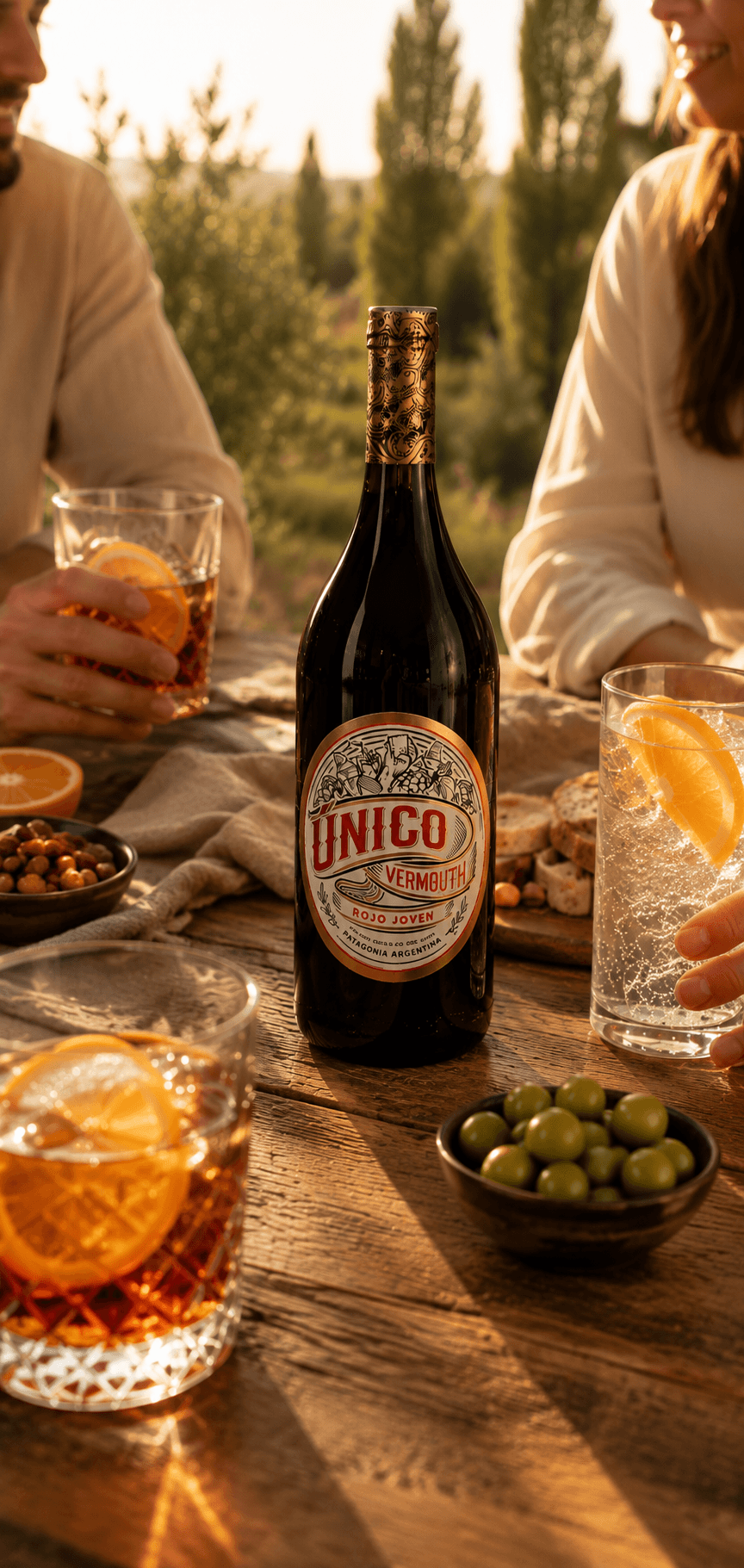 Botella y copa de Único Vermouth sobre una mesa patagónica al atardecer
